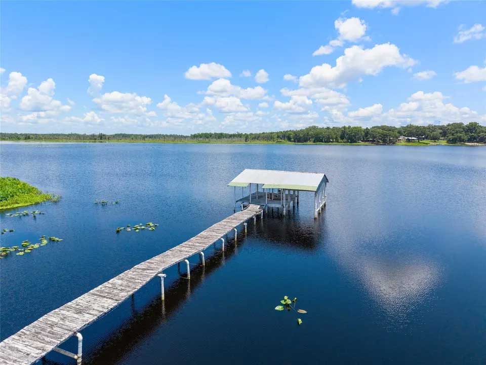 A long wooden dock stretches across a calm Florida lake beneath a bright blue sky, capturing the relaxed outdoor atmosphere often paired with canned wine and hard seltzer drinks during waterfront gatherings and weekend getaways.
